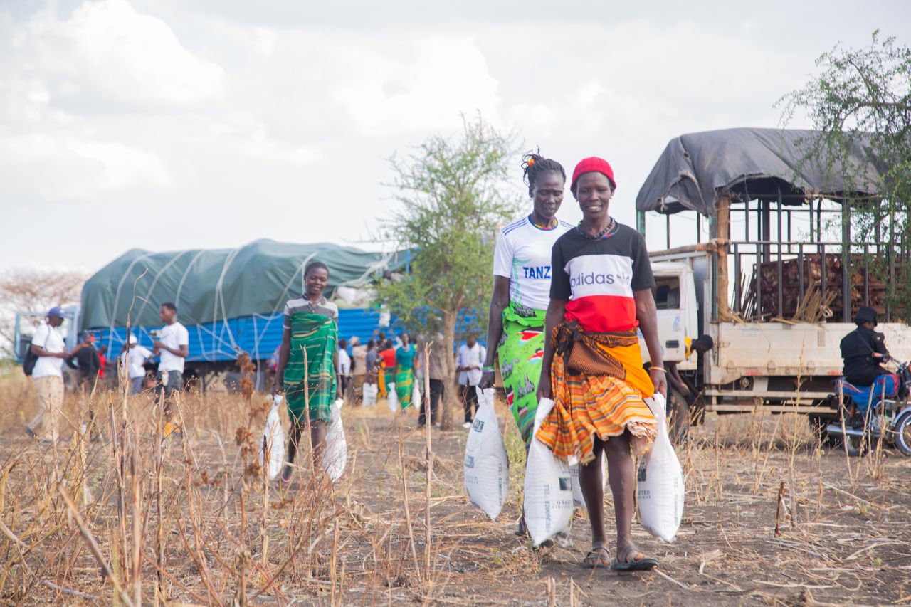 why-choose-us People receiving aid supplies in a rural African community with a truck in the background.
